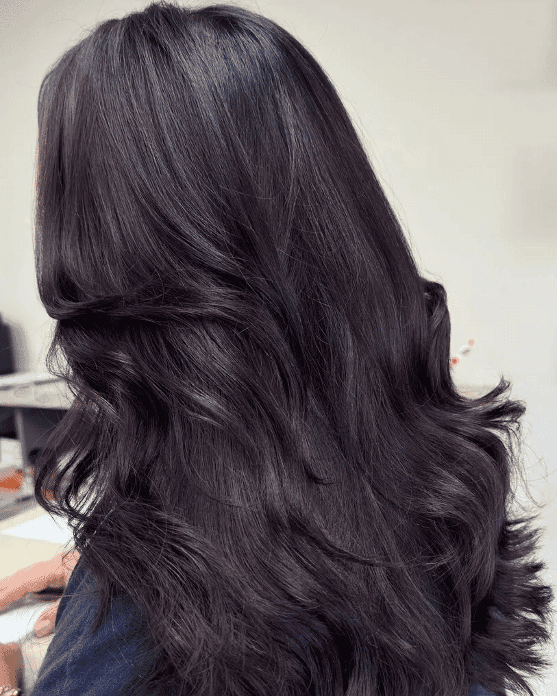 Dark wavy hair with a hint of purple, styled for a smooth, voluminous look.