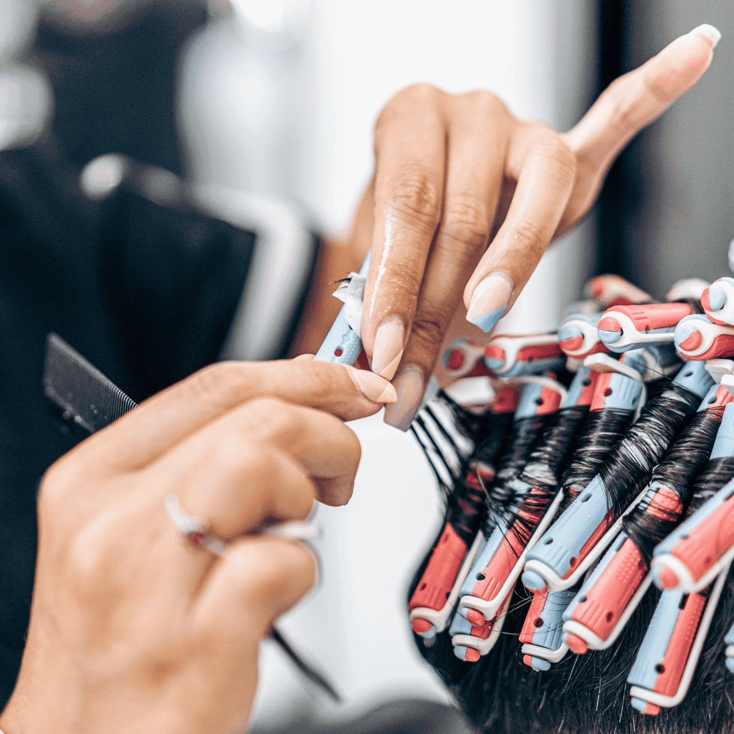 Hands arranging hair curlers in a salon setting.